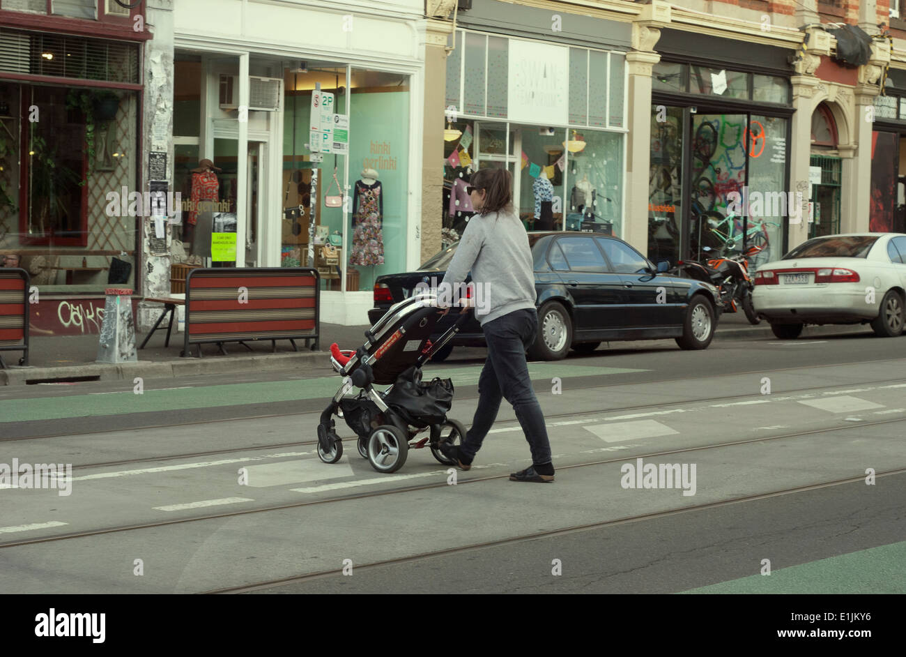 Giovane madre spingendo la PRAM in Brunswick Street Fitzroy Melbourne Australia Foto Stock