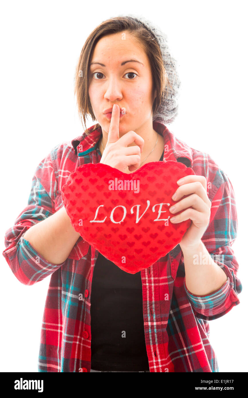 Giovane donna azienda forma di cuore con un dito sulle labbra Foto Stock