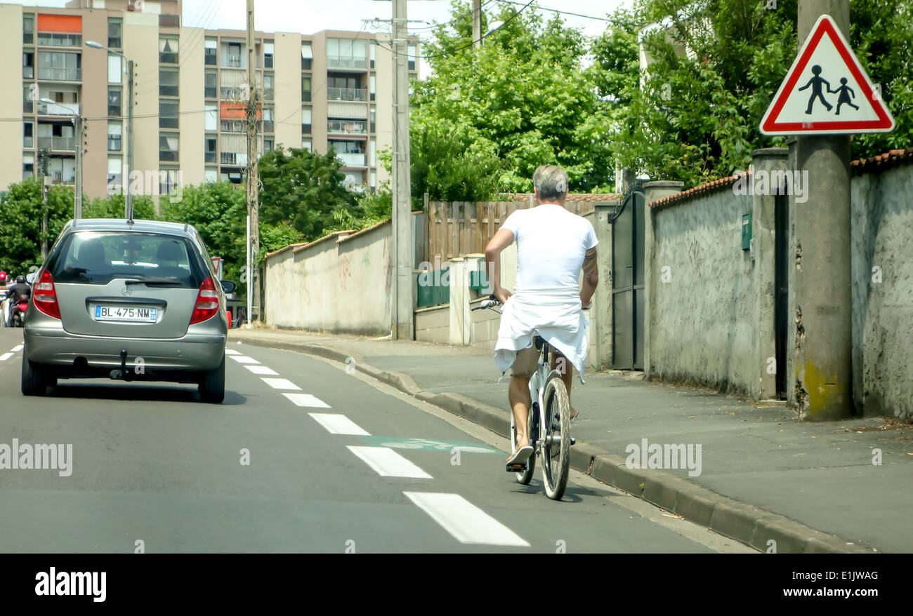 Un Uomo in camicia con un asciugamano bianco intorno alla vita, pedali sulla sua moto in città Foto Stock