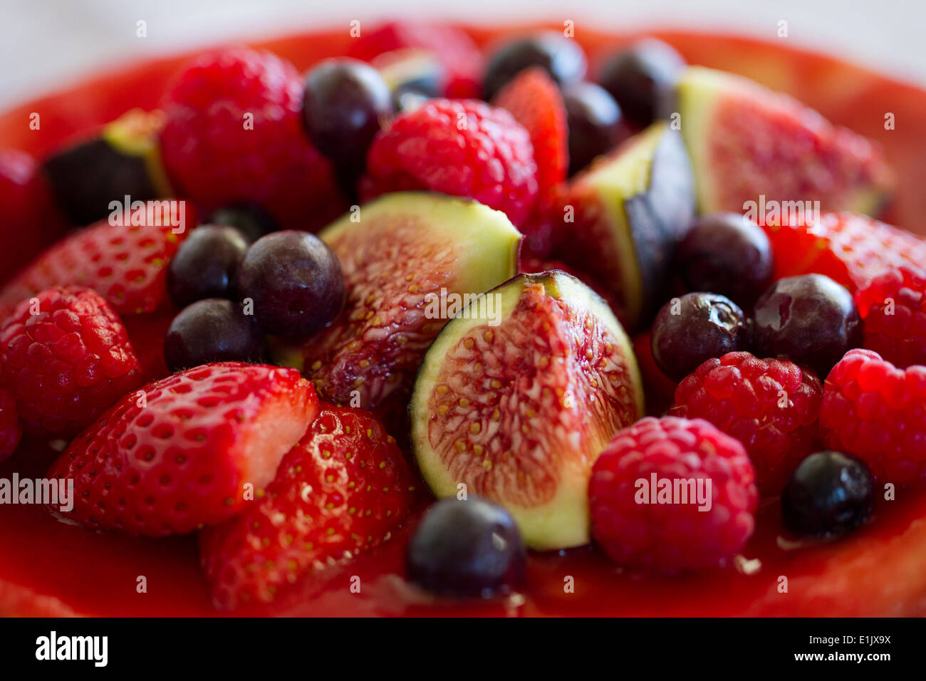 Un delizioso cheesecake cotto sormontato da un assortimento di frutti sani e fette di figg. Foto Stock