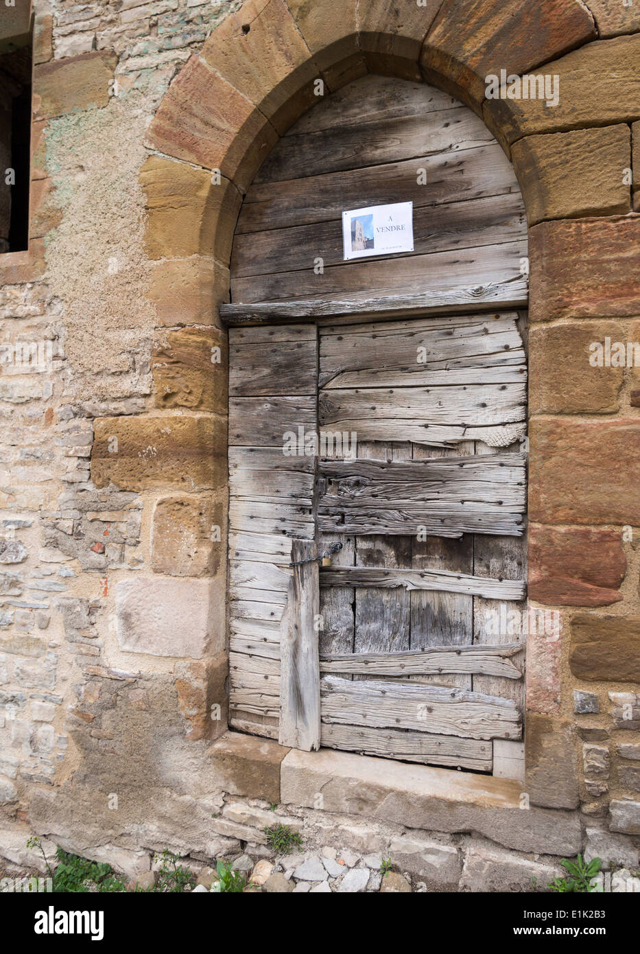 A Vendre - in vendita. Un piccolo in vendita segno su un antico intavolato portale in pietra. Cordes sur Ciel, Tarn, Francia Foto Stock