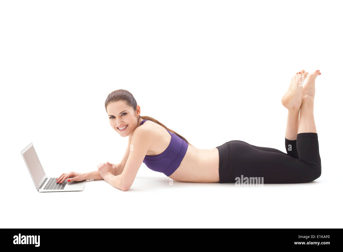 Modello rilasciato donna sdraiata sul pavimento con un computer portatile Studio shot. Foto Stock