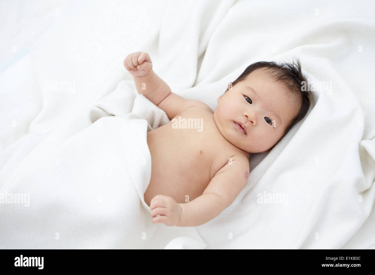 Modello rilasciato bambina giacente sulla biancheria bianca verticale. Foto Stock