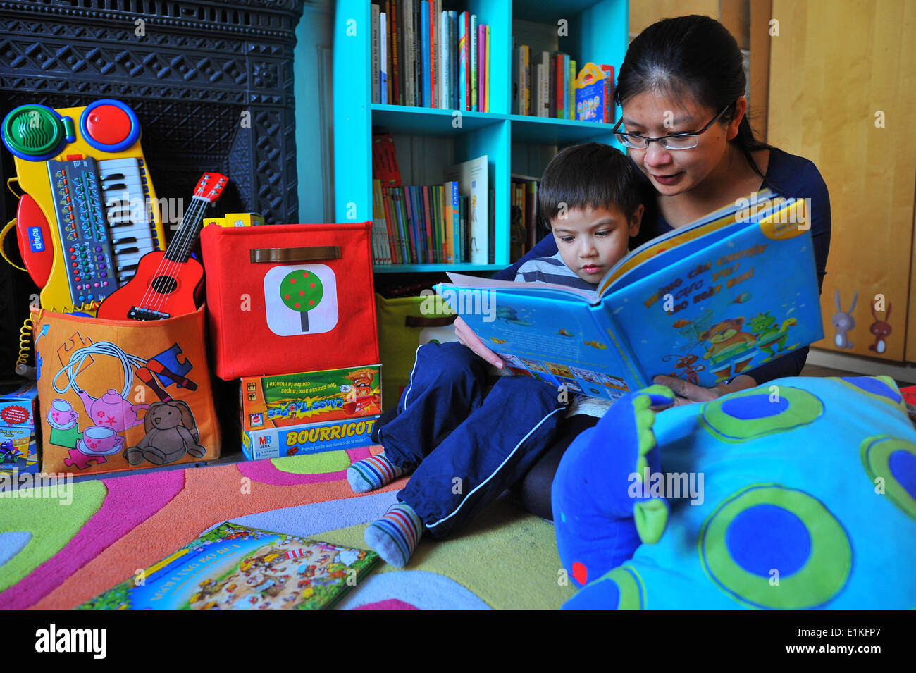La madre e il bambino a leggere un libro nel ragazzo in camera da letto Foto Stock
