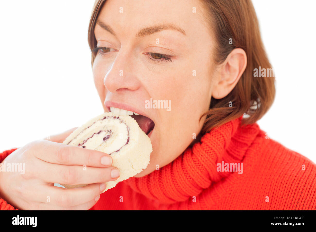 Modello rilasciato donna mordere in un pezzo di torta. Foto Stock