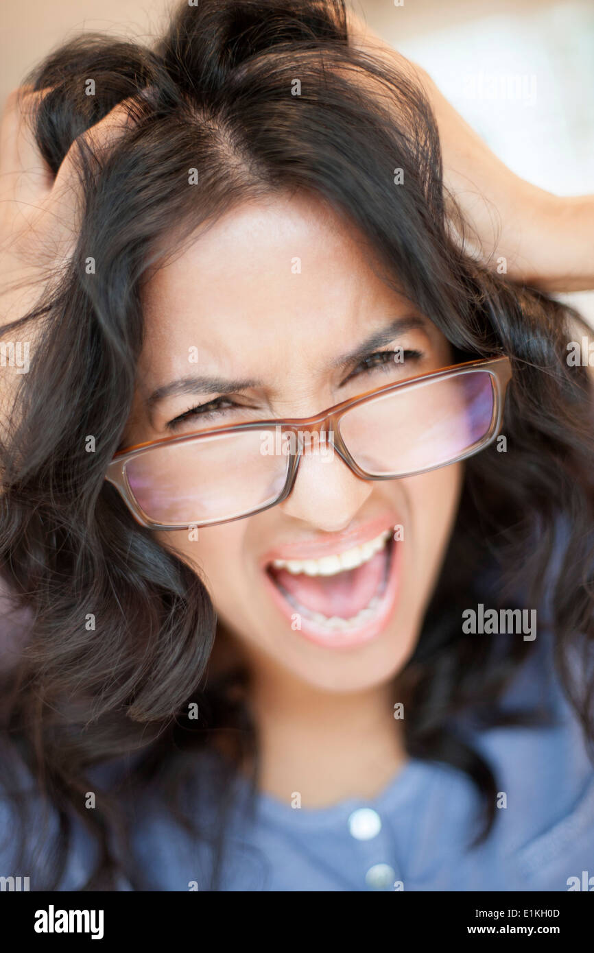 Modello rilasciato donna che indossa occhiali con le mani nei capelli. Foto Stock