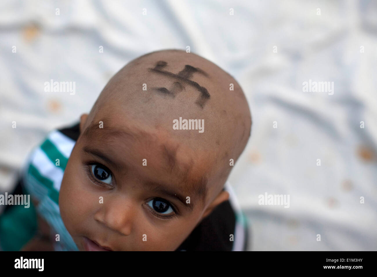 Ragazzo indù con la svastica sulla sua testa rasata Foto Stock