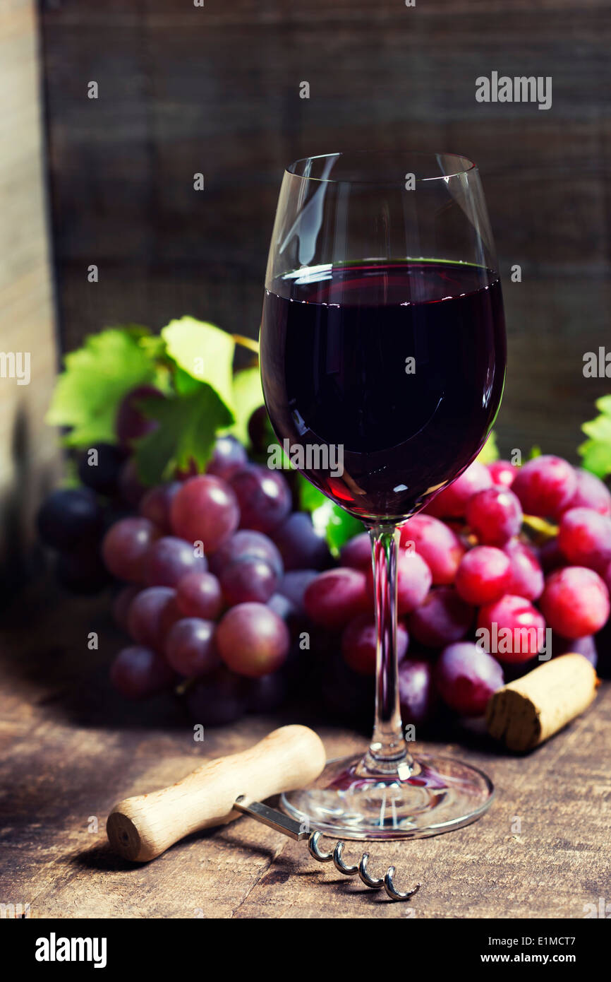 Vino rosso e uva rossa su sfondo di legno. Foto Stock