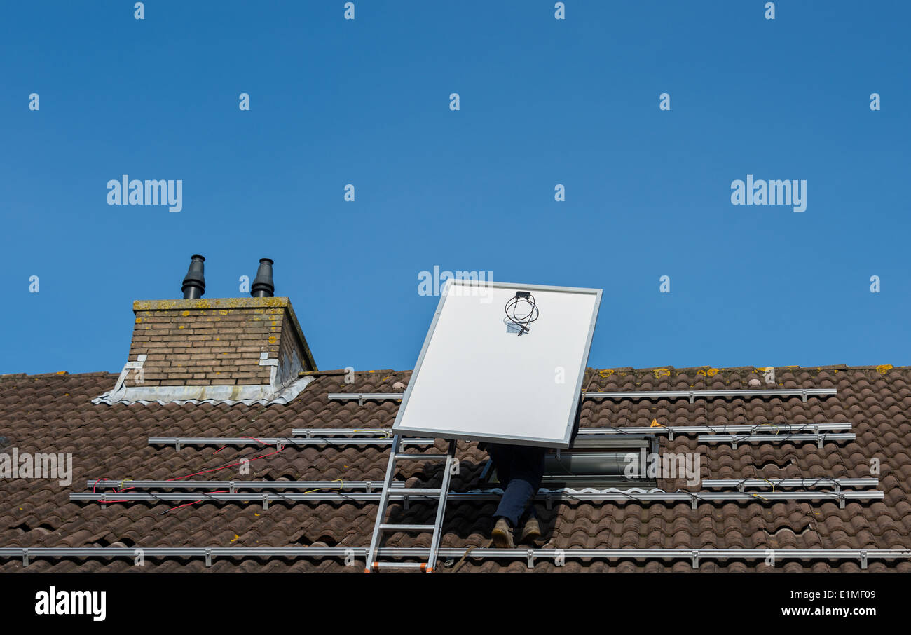 L'uomo salire la scala del tetto con pannello solare Foto Stock