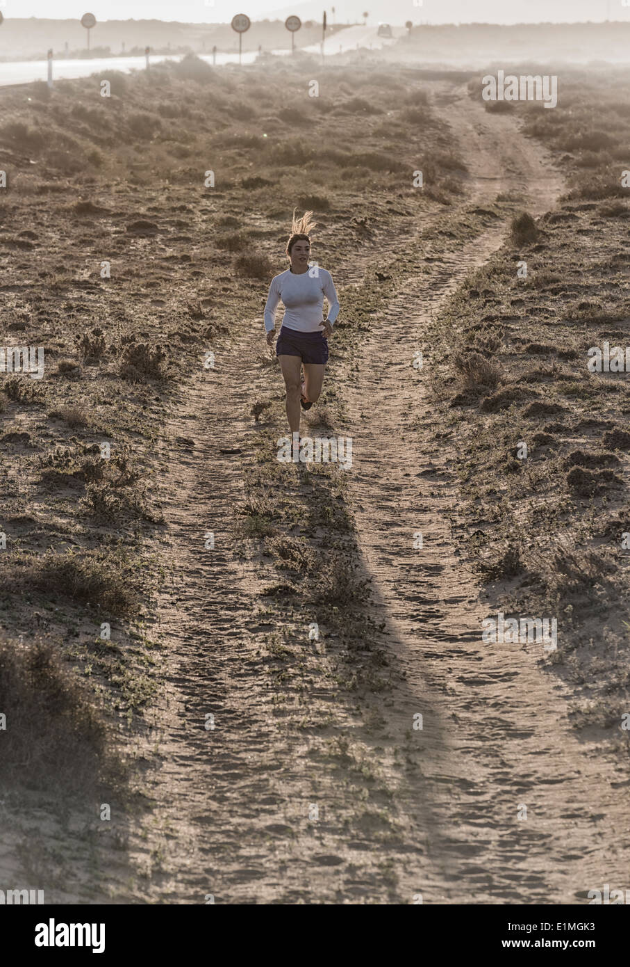 Donna correndo giù per una strada sterrata. Lanzarote, Isole Canarie, Spagna, Europa. Foto Stock