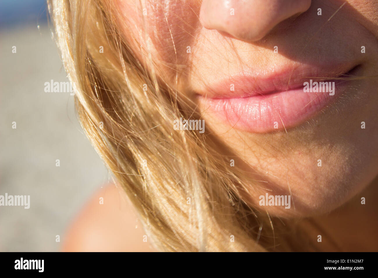 Ragazza donna labbra viso capelli biondo closeup luce solare all'esterno zoom allegro sorridente giovane Foto Stock