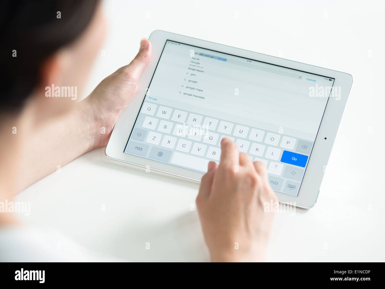 Donna che mantiene un bianco Apple iPad aria e la digitazione per la ricerca di Google nella pagina web nel browser Safari Foto Stock