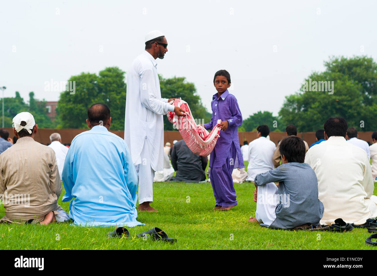 Bambini e adulti non vedenti mendicanti tra la gente seduta per preghiere su Eid, Lahore, Pakistan Foto Stock