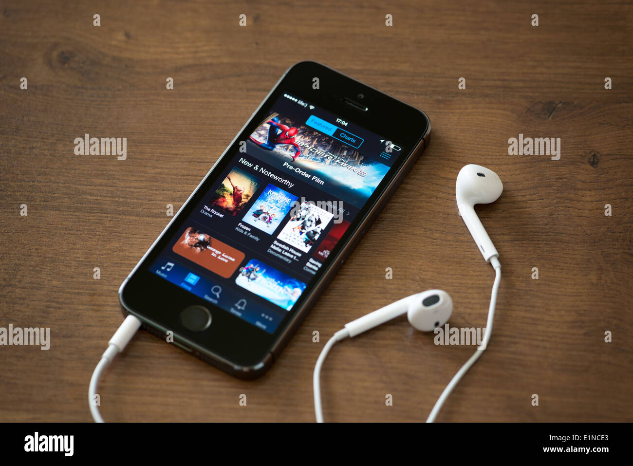Nuovo Apple iPhone 5S con iTunes store applicazione sullo schermo giacente su un banco con le cuffie Foto Stock