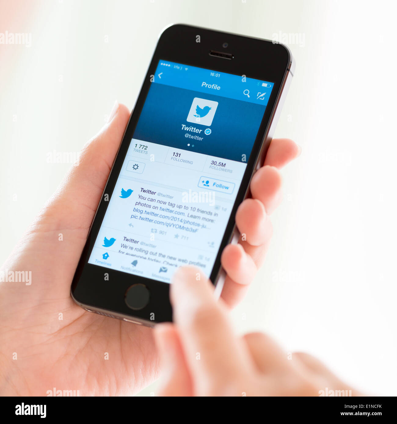 Persona in possesso di un marchio nuovo Apple iPhone 5S con il profilo Twitter sullo schermo Foto Stock
