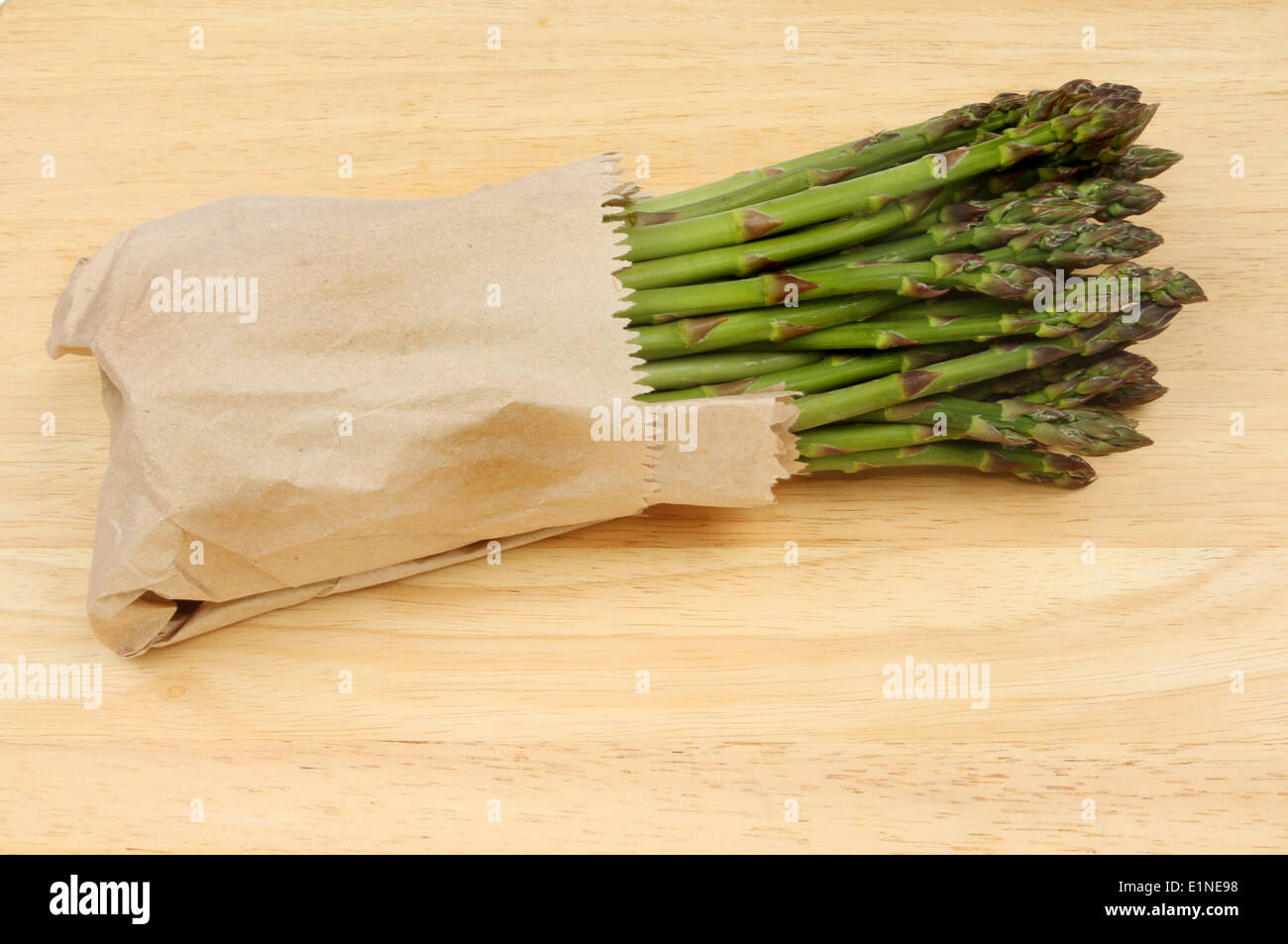 Gli asparagi avvolto in carta marrone su una tavola di legno Foto Stock