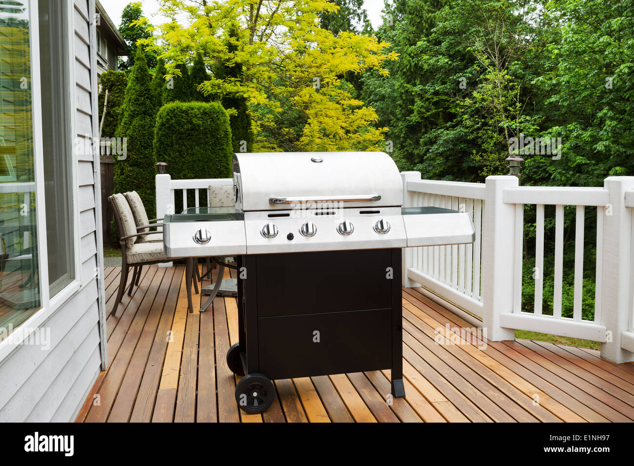 Closeup foto orizzontale della griglia per il barbecue su open cedar patio con alberi di stagione in piena fioritura in background Foto Stock