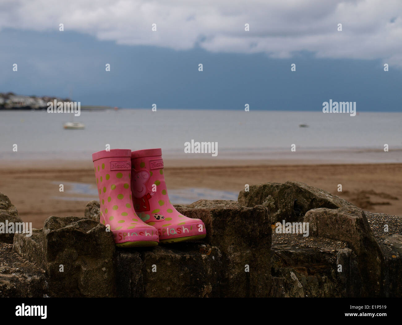 Coppia di rosa per bambini stivali wellington su una parete in spiaggia, Instow, Devon, Regno Unito Foto Stock