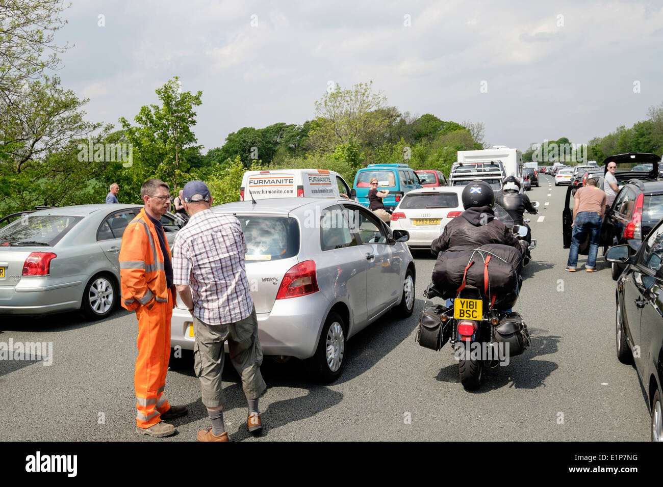 Persone in piedi sulla carreggiata della strada al di fuori di veicoli fermi in un ingorgo sull'autostrada M6, a causa di un incidente causando lunghi ritardi. Lancashire England Regno Unito Foto Stock