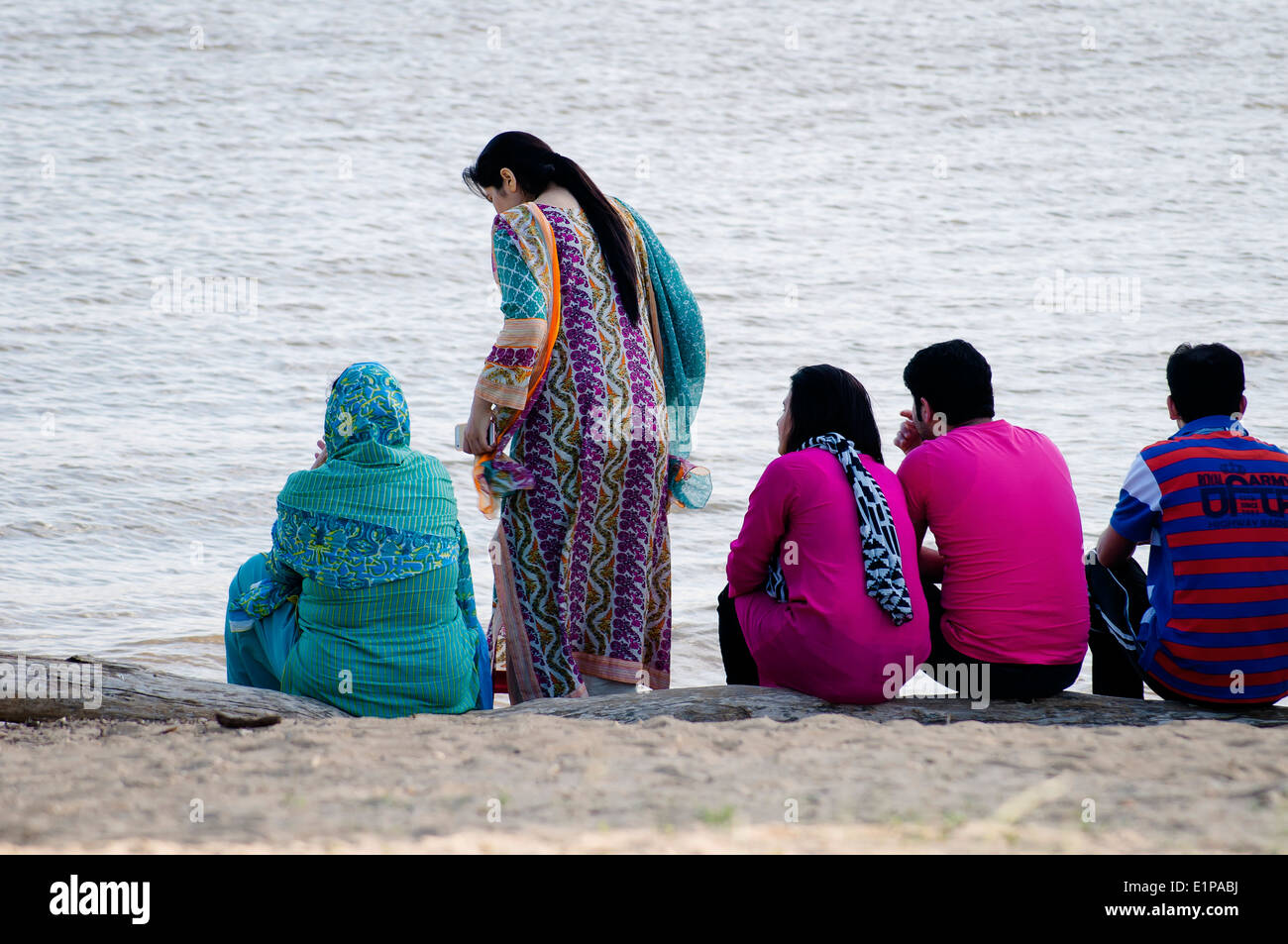 Giovani americani asiatici seduti sulla riva del fiume Delaware nel parco, Philadelphia, Stati Uniti Foto Stock