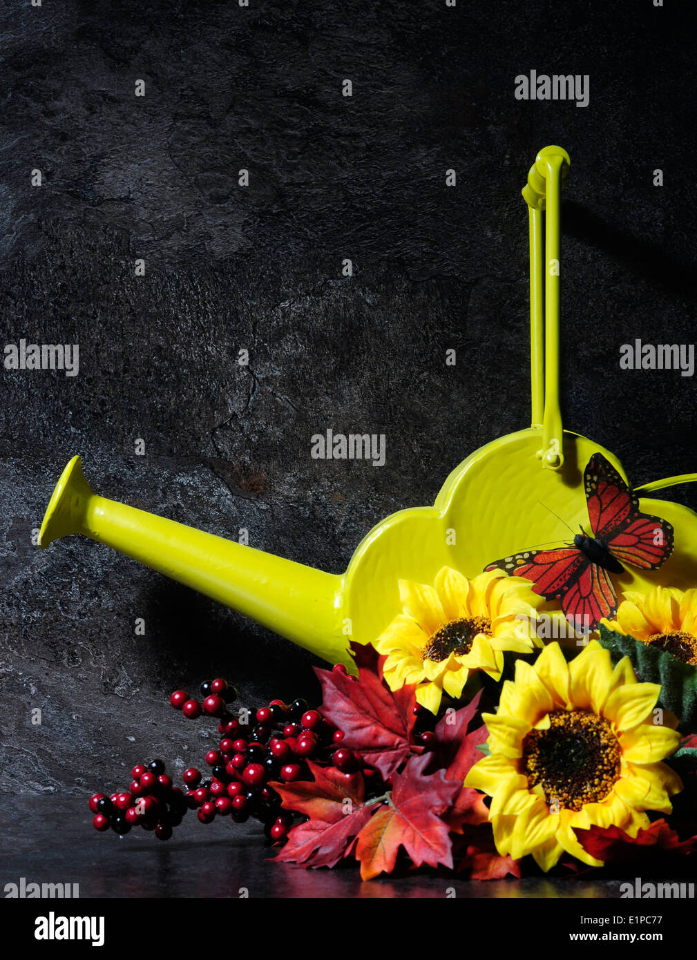 Impostazione di autunno ancora in vita con stile vintage giallo annaffiatoio e caduta foglie, fiori e farfalla Foto Stock