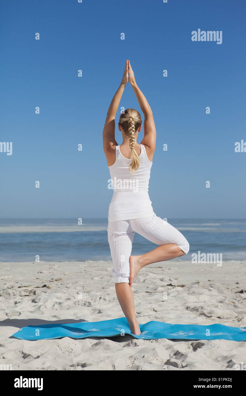 Donna bionda in piedi in posa ad albero sulla spiaggia Foto Stock