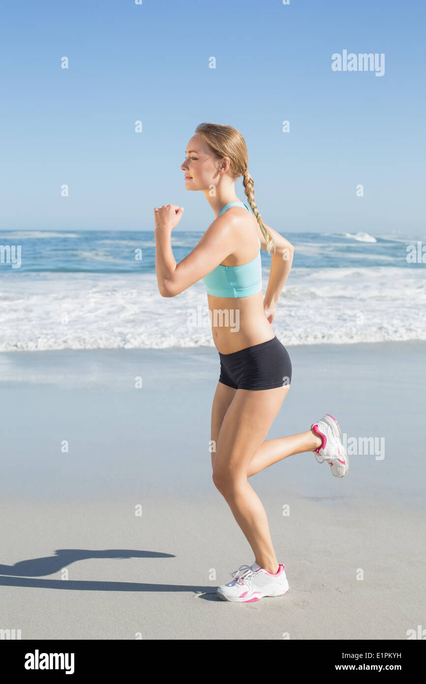 Montare la bionda jogging sulla spiaggia Foto Stock