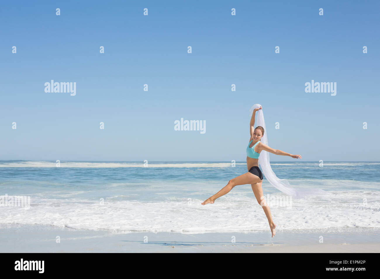 Montare donna jumping con garbo sulla spiaggia con sciarpa Foto Stock