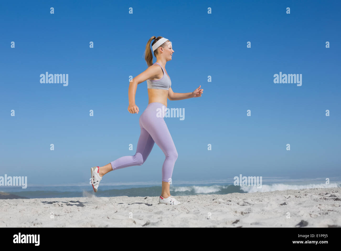 Bionda sportiva sulla spiaggia jogging Foto Stock