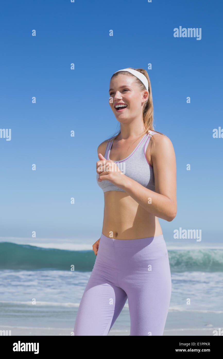 Sporty felice bionda jogging sulla spiaggia Foto Stock