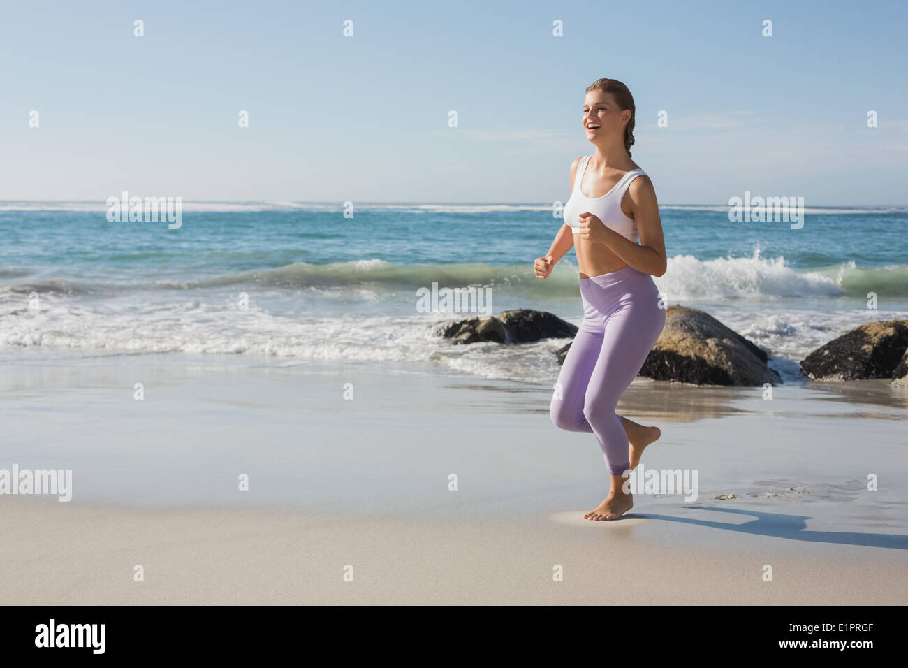 Bionda sportiva jogging sulla spiaggia Foto Stock