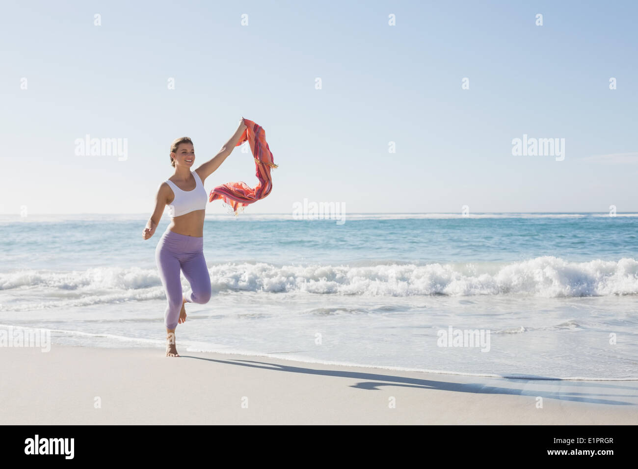 Bionda sportiva jogging sulla spiaggia con una sciarpa Foto Stock