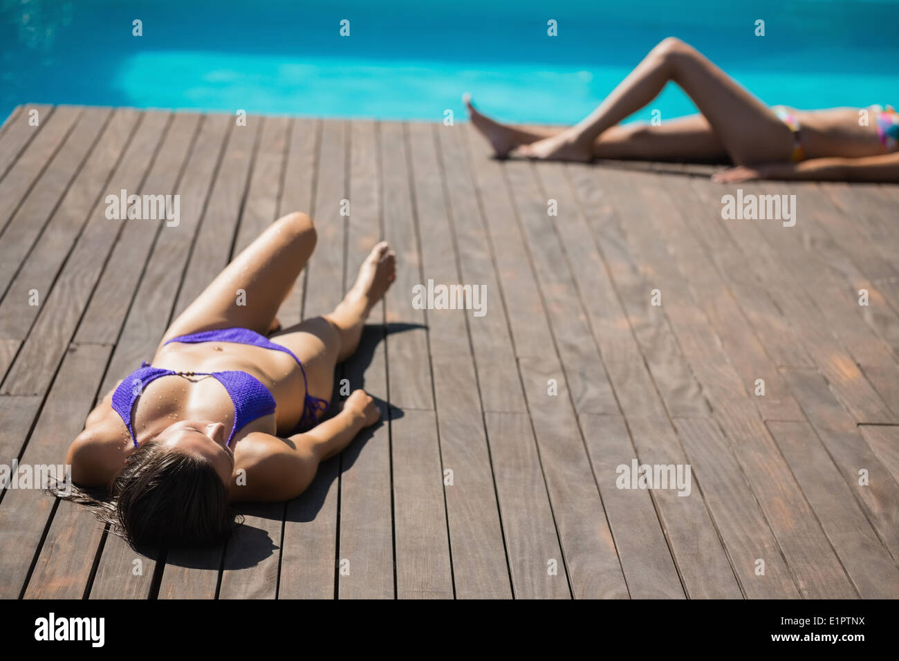 Donne in bikini sdraiato a prendere il sole a bordo piscina Foto Stock