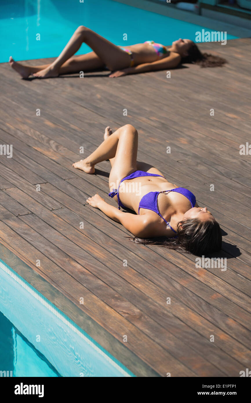Donne in bikini sdraiato a prendere il sole a bordo piscina Foto Stock