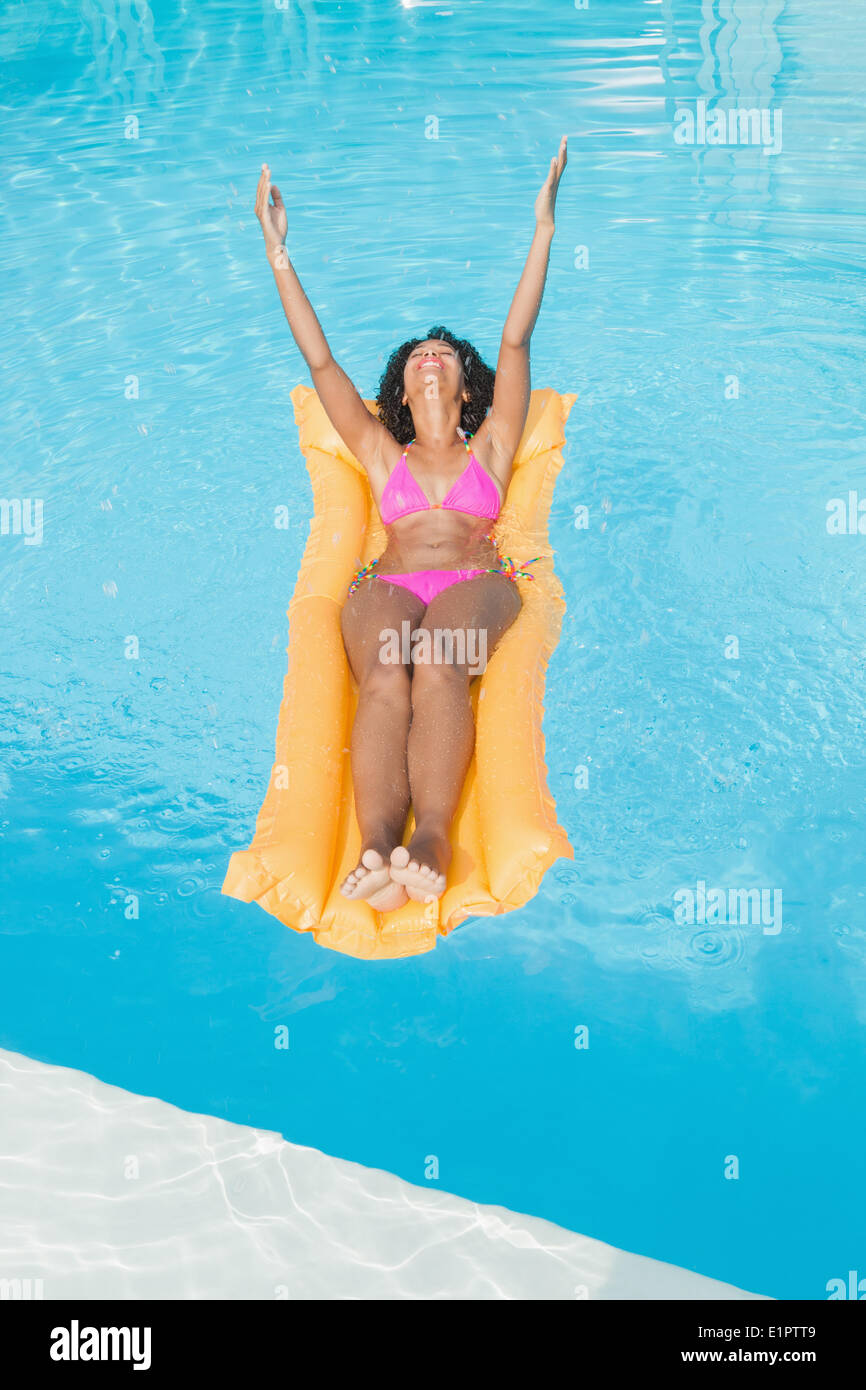Excited donna in rosa bikini giacente su lilo in piscina Foto Stock