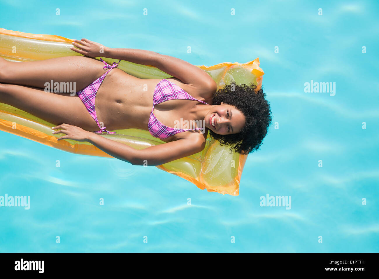 Donna felice giacente su lilo in piscina Foto Stock
