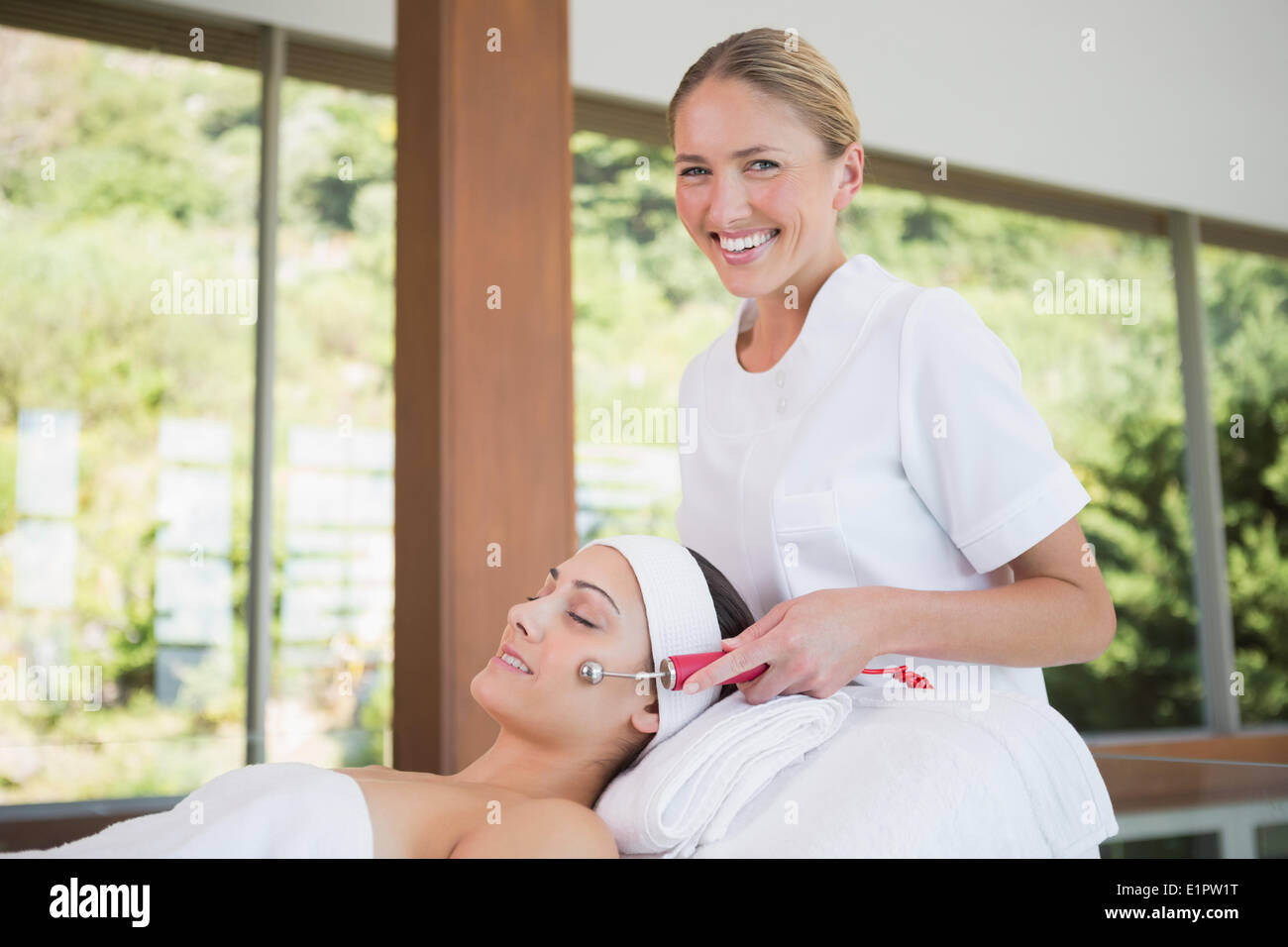 Brunette getting micro aiuto di dermoabrasione con terapista sorridente in telecamera Foto Stock