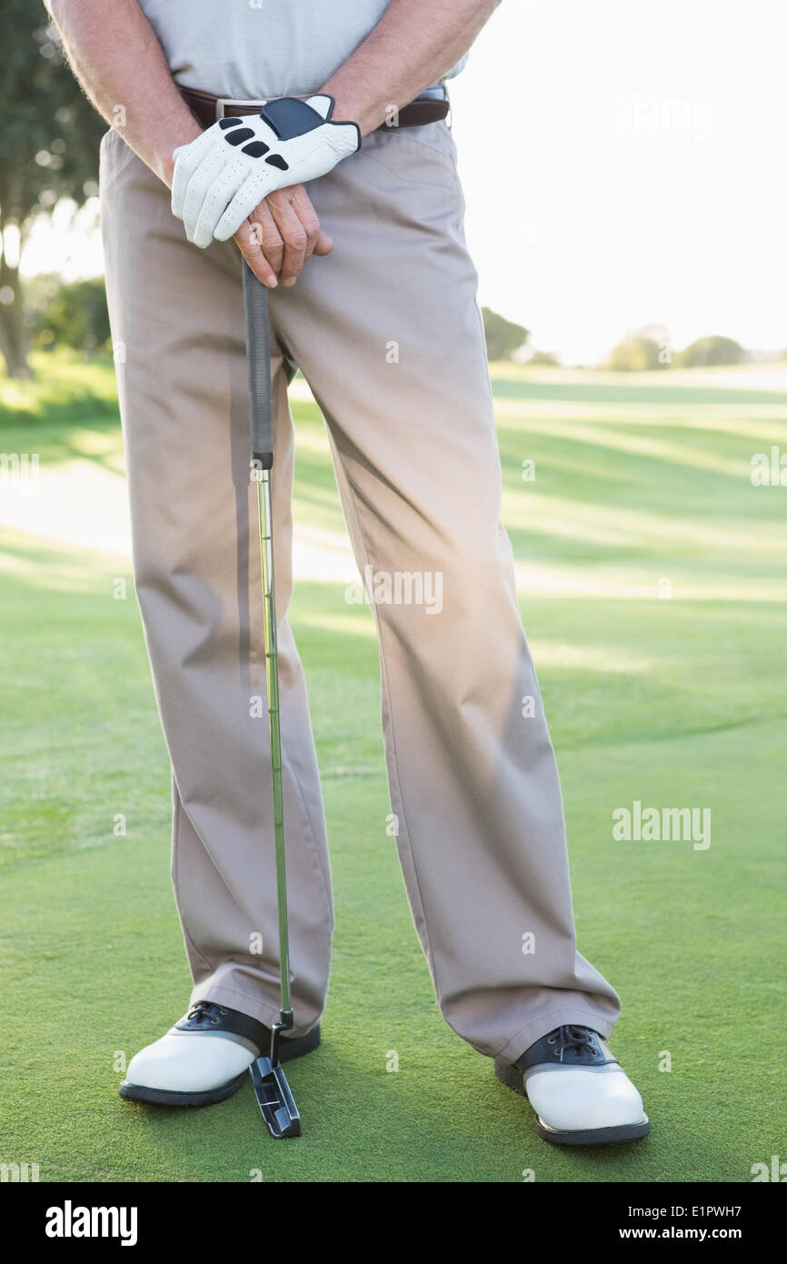 La metà inferiore del giocatore di golf in piedi con club Foto Stock