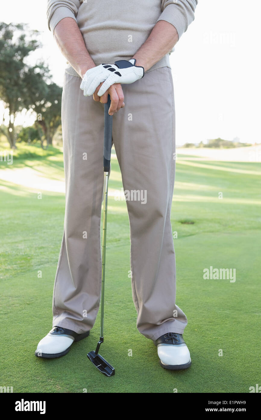 Sezione bassa del giocatore di golf in piedi con club Foto Stock