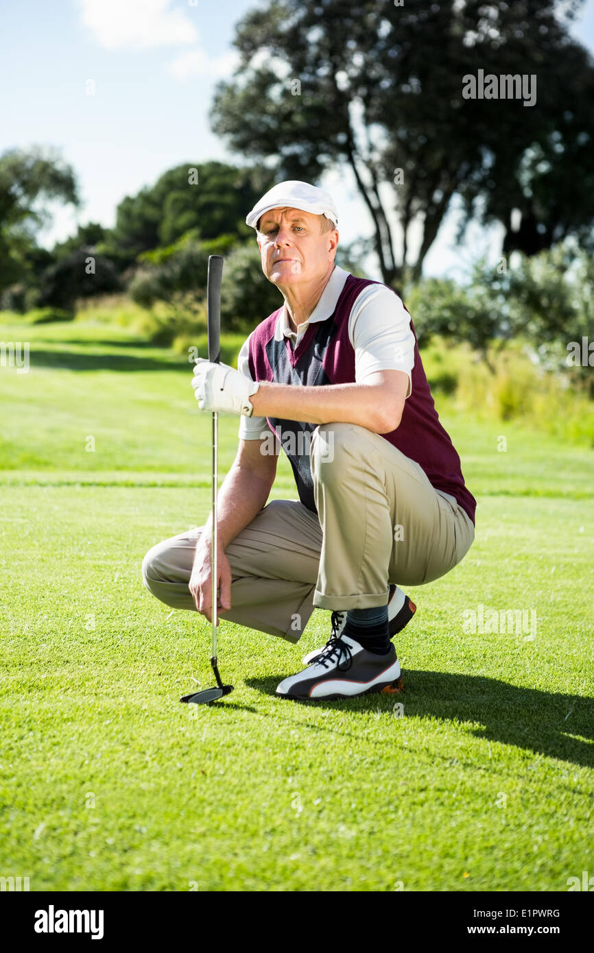 Il Golfer inginocchiato tenendo la sua golf club Foto Stock