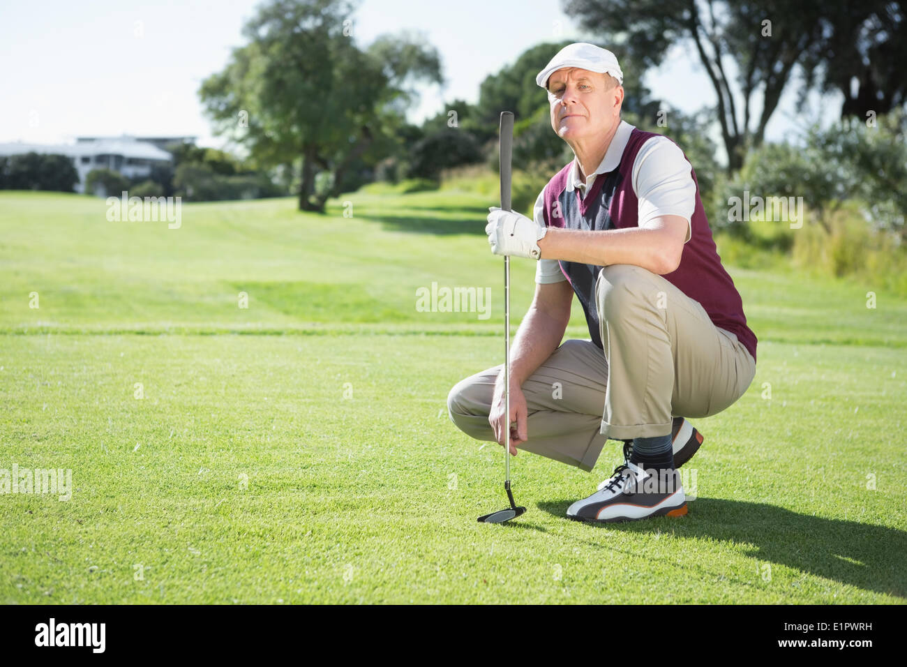 Fiducioso il golfer inginocchiato tenendo la sua golf club Foto Stock