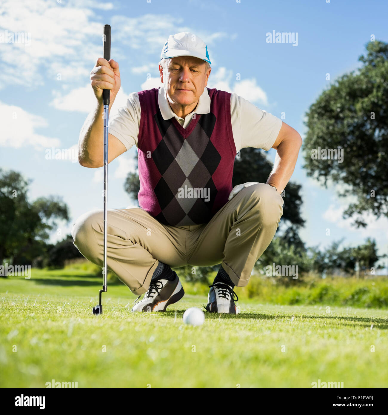 Il Golfer inginocchiato guardando la sfera in oro Foto Stock