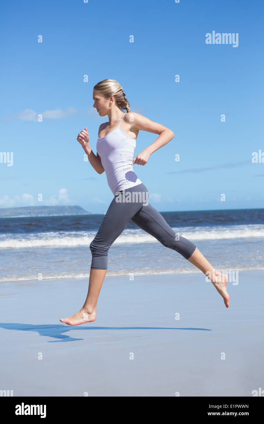Montare focalizzato bionda jogging sulla spiaggia a piedi nudi Foto Stock