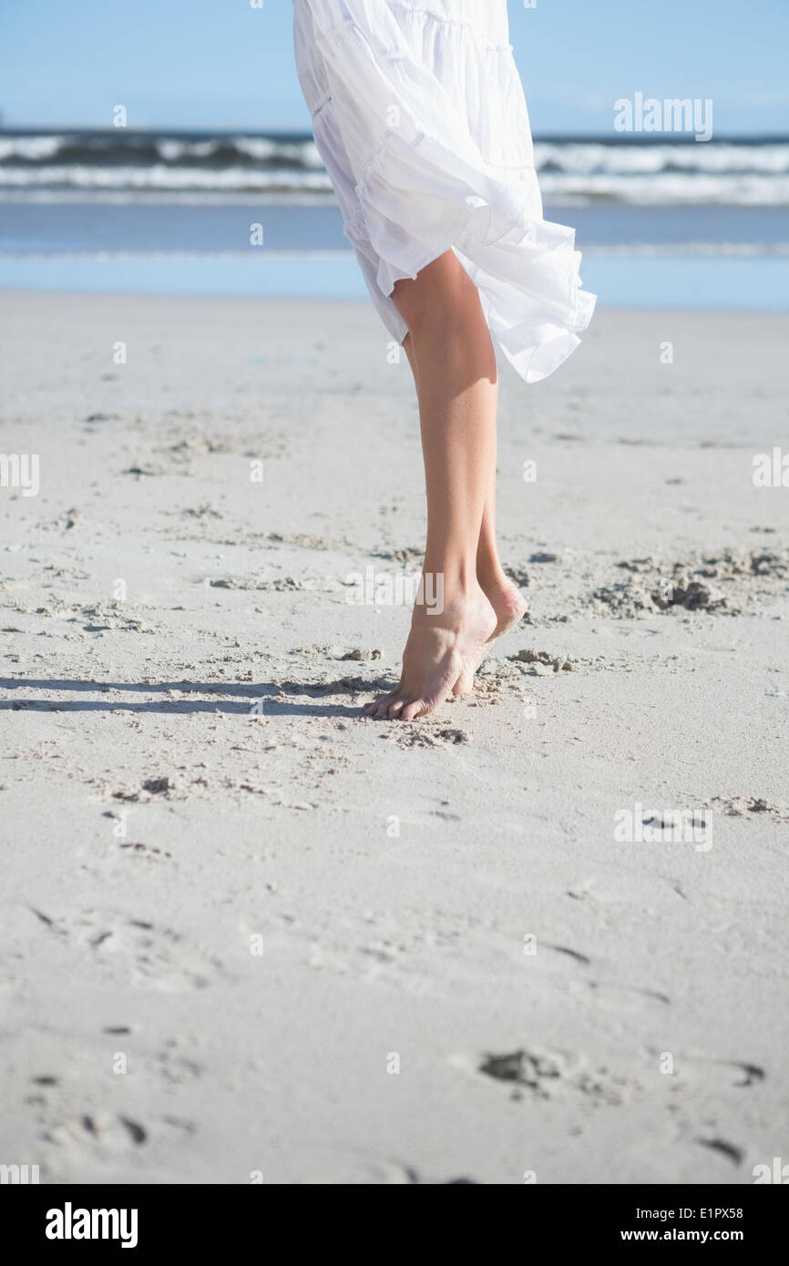 Donna in abito bianco stepping sulla spiaggia Foto Stock