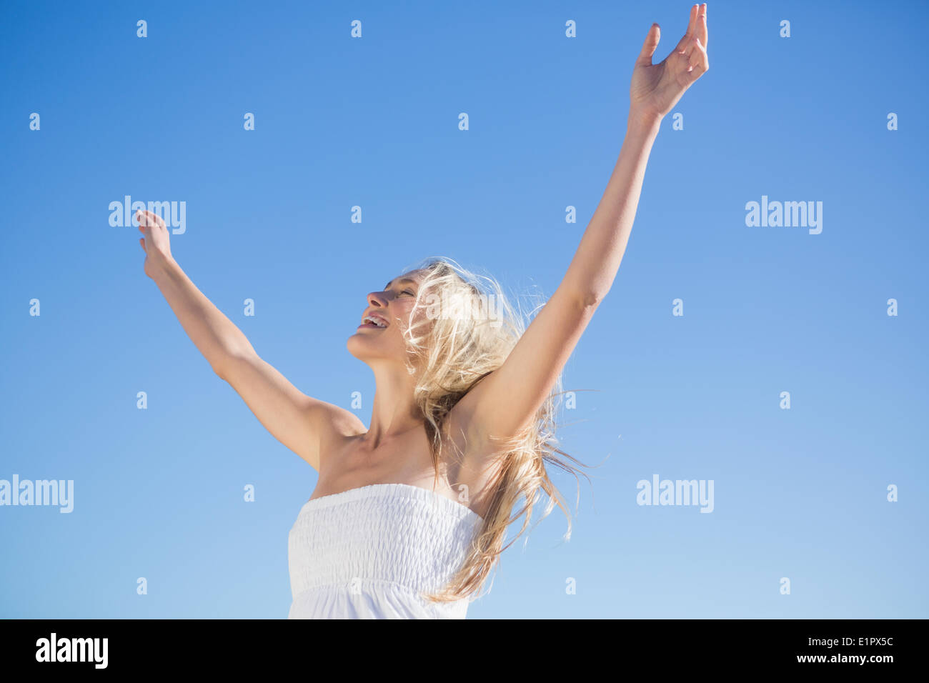 Donna in abito bianco in piedi con le braccia tese Foto Stock