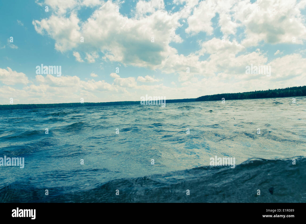 Increspate acque fredde di foresta lago sotto il blu cielo molto nuvoloso Foto Stock