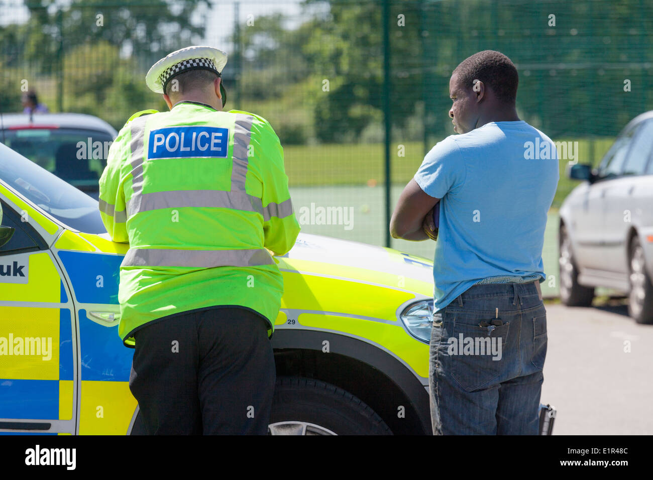 Funzionario di polizia a parlare con uomo nero da auto della polizia. Foto Stock