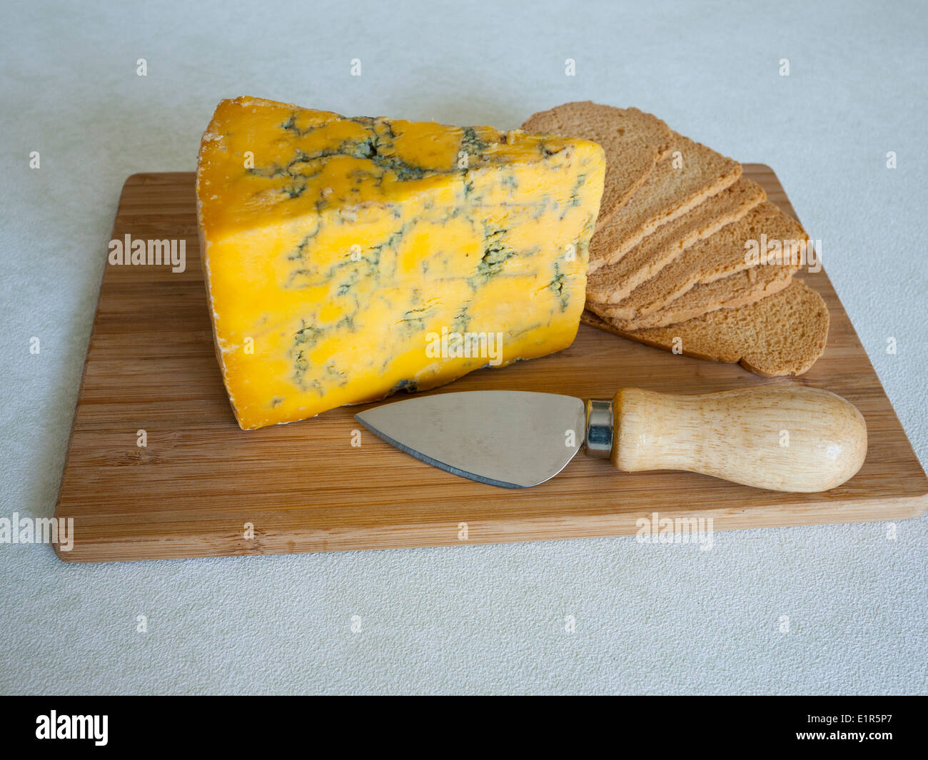 Blue Shropshire piena formaggio grasso sulla scheda di formaggio con wheatbread tostato e il coltello. Foto Stock