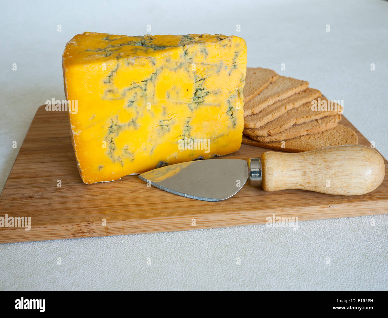 Blue Shropshire piena formaggio grasso sulla scheda di formaggio con wheatbread tostato e il coltello. Foto Stock