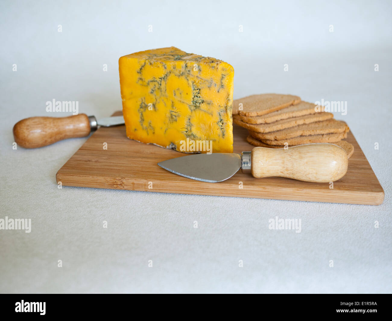 Blue Shropshire piena formaggio grasso sulla scheda di formaggio con wheatbread tostato e coltelli. Foto Stock
